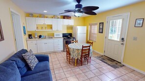 Cozy living space with a kitchenette, sofa, dining table, and ceiling fan.