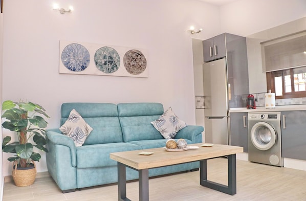 Ein modernes Wohnzimmer mit einem blauen Sofa, einem Couchtisch und einer großen Pflanze.