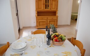 Mesa de jantar posta com pratos, copos de vinho e uma cesta de frutas.