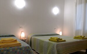 Quarto com duas camas, cada uma com um edredom estampado e uma luminária ao lado.