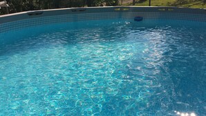 En klarblå pool med kakel runt kanten och ett föremål som flyter i mitten.