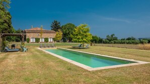 A pool area with lounge chairs and a pergola, surrounded by a grassy lawn and trees. - Costabravaforrent Tallada (La Tallada d'Empordà)