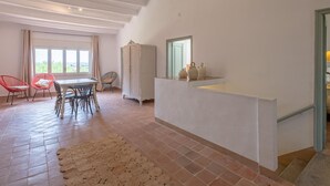 A spacious room with a high ceiling, a dining area with a table and chairs, a wardrobe, and a view through a window. - Costabravaforrent Tallada (La Tallada d'Empordà)