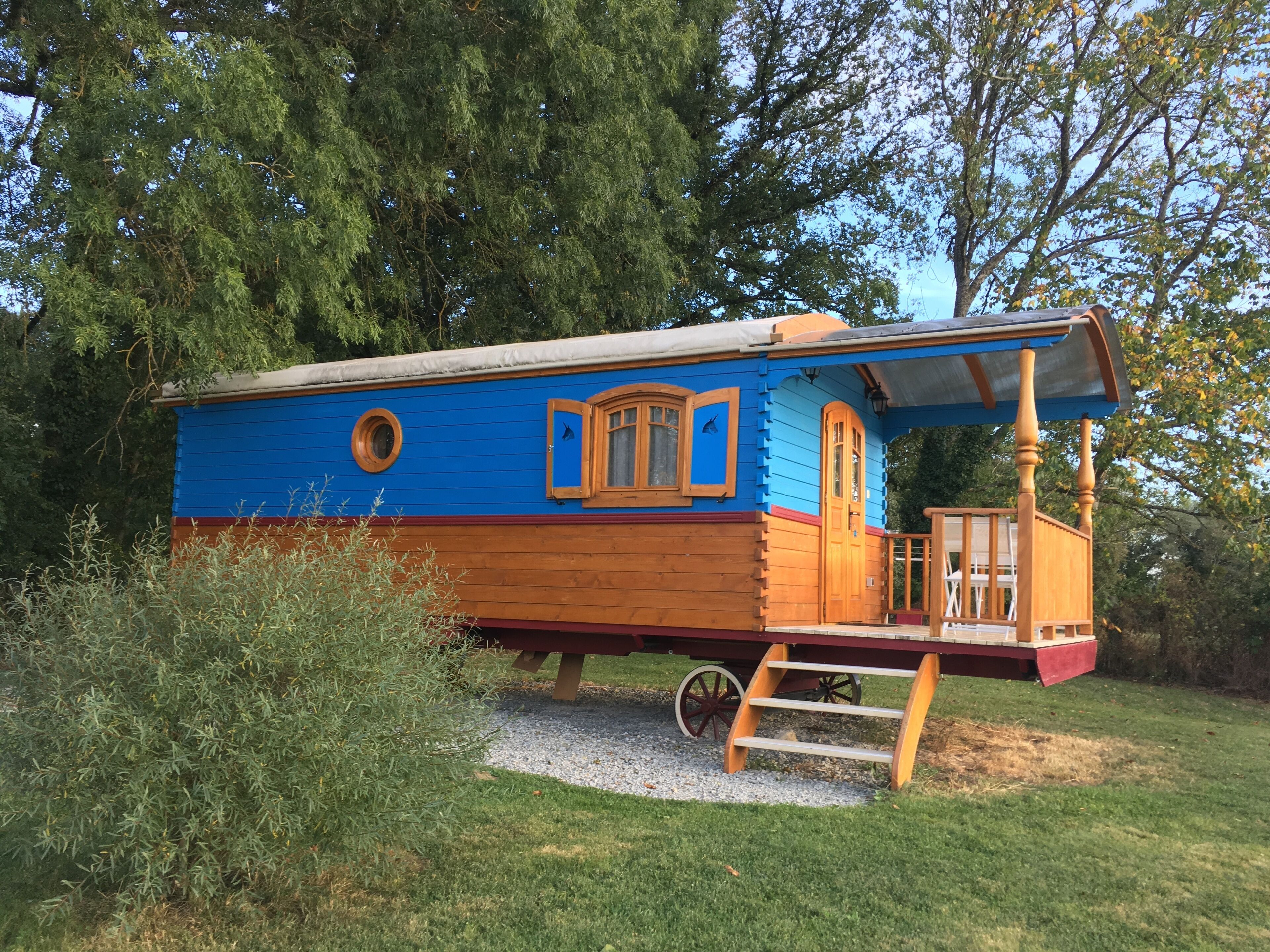 Ein blaues, holzverkleidetes Hausboot mit Veranda, Fenstern und einer Tür.