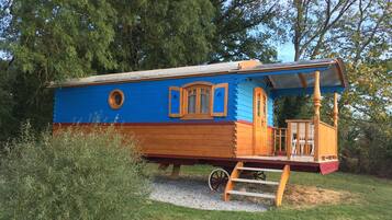 Ein blaues, holzverkleidetes Hausboot mit Veranda, Fenstern und einer Tür.