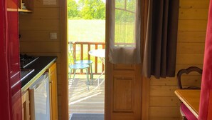 Una cabaña de madera con cocina, comedor y puerta que da a una terraza al aire libre.