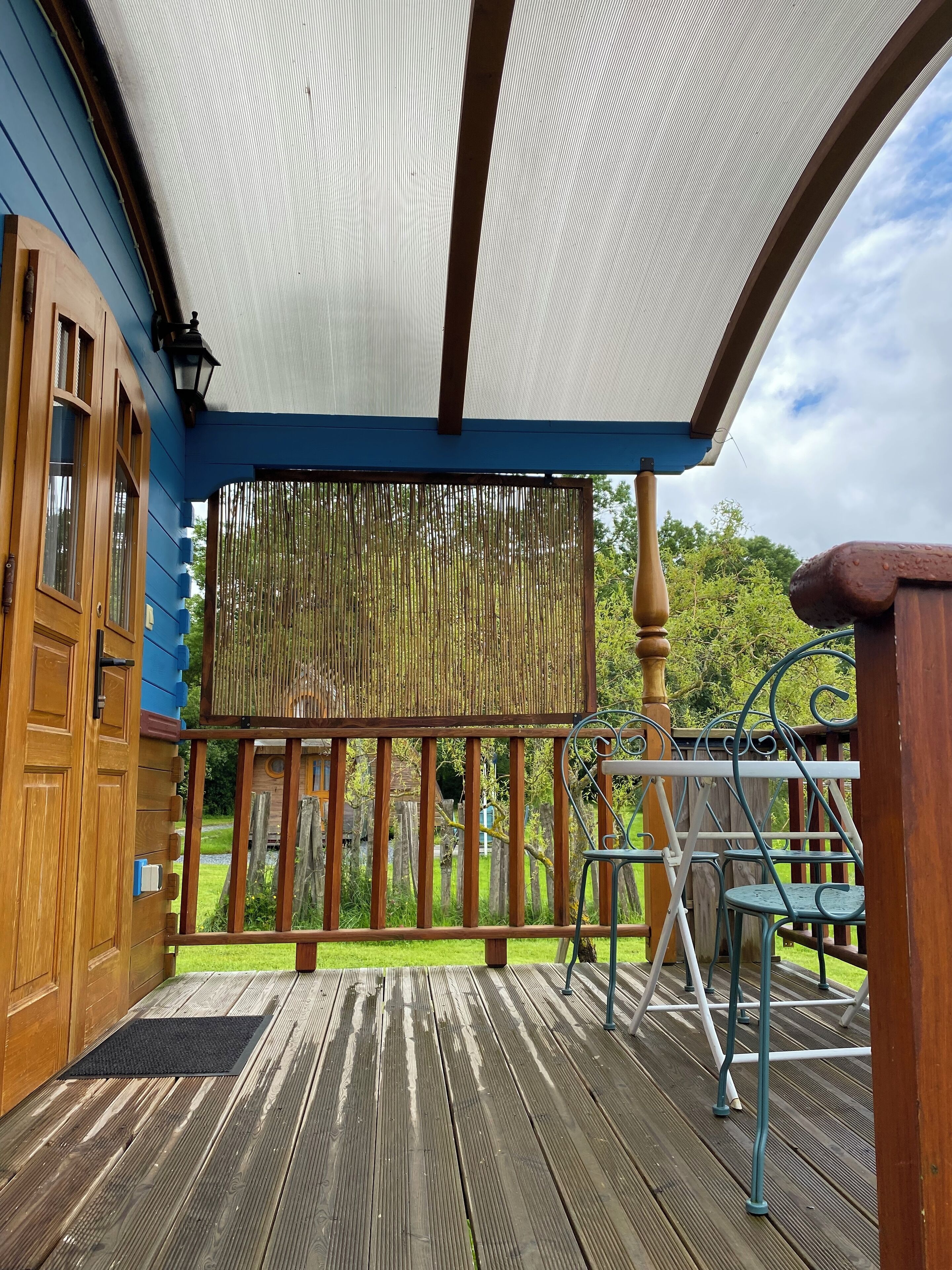 Een houten terras met een pergola en uitzicht op een tuin.