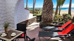 Un patio con mesa y sillas, una palmera y vista a la playa.