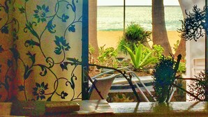 Una habitación con vista a la playa, una planta en maceta y una silla.