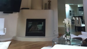 Una sala de estar con chimenea, techo de madera y un televisor de pantalla plana montado en la pared.
