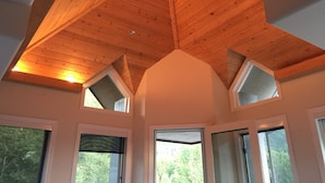 Una habitación con techo de madera inclinado, varias ventanas y un tragaluz visible.