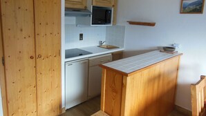 Una cocina compacta con armarios de madera, microondas, lavavajillas y una pequeña isla.