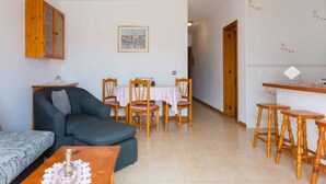 A cozy living room with a sofa, a coffee table, and a dining area with chairs and a table. - Sunny 2-Bedrooms With Large Terrace. WiFi (Arona)