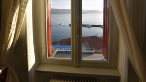A room with a window overlooking a body of water and a distant shoreline.