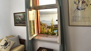 A cozy room with a sofa, a small table, a window with curtains, and a framed picture on the wall.