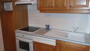 Uma cozinha com armários de madeira, micro-ondas, fogão, lava-louças e pia.