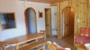 Interior de madeira com uma mesa de jantar, bancos e uma cadeira estofada.