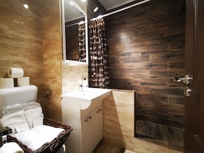 A bathroom with a wooden wall, a white sink, a mirror, and a shower curtain with text.