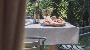 Une table dressée à l’extérieur, avec une bouteille, des verres et une assiette de nourriture.