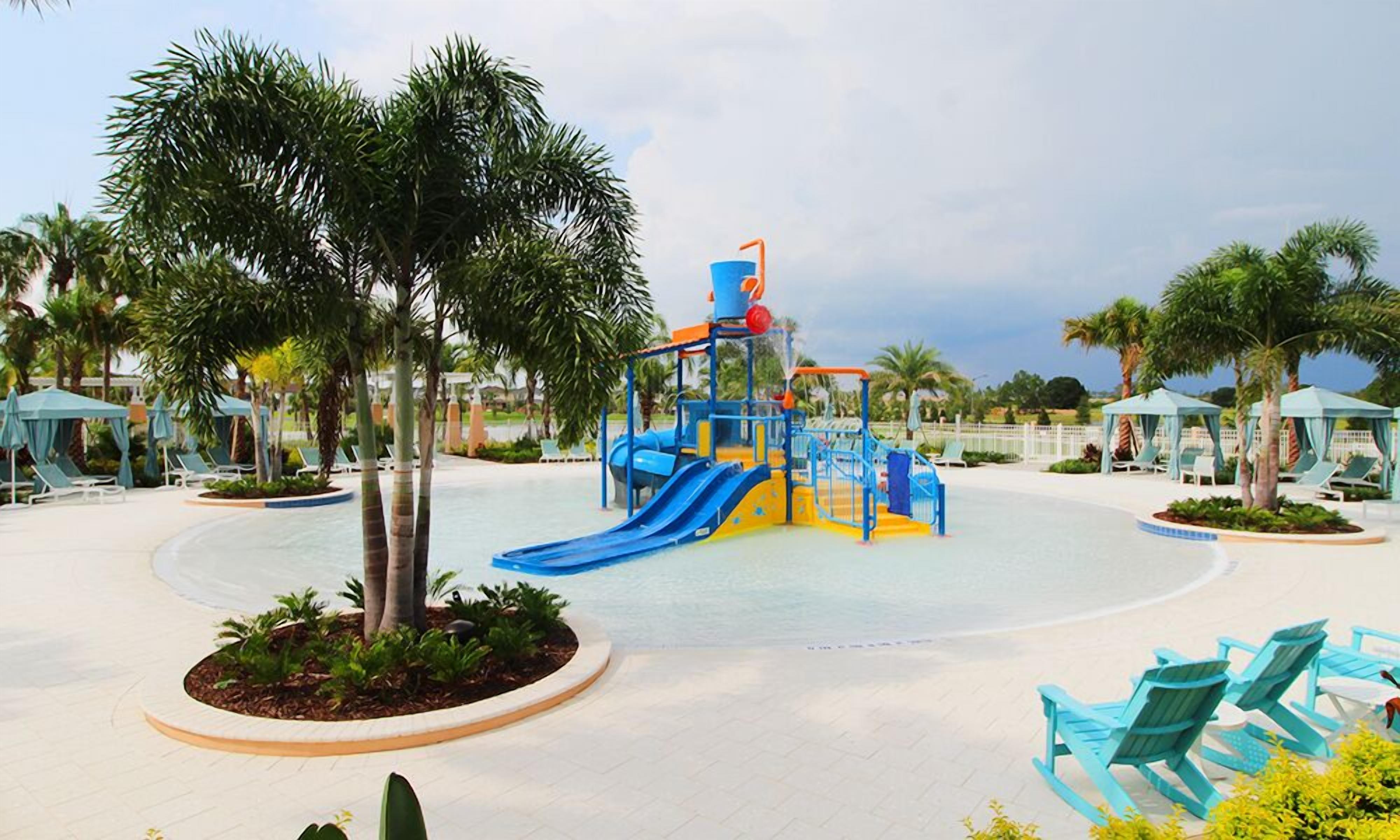 Ein Wasserpark mit einer blauen und gelben Spielkonstruktion, Palmen und Liegestühlen.