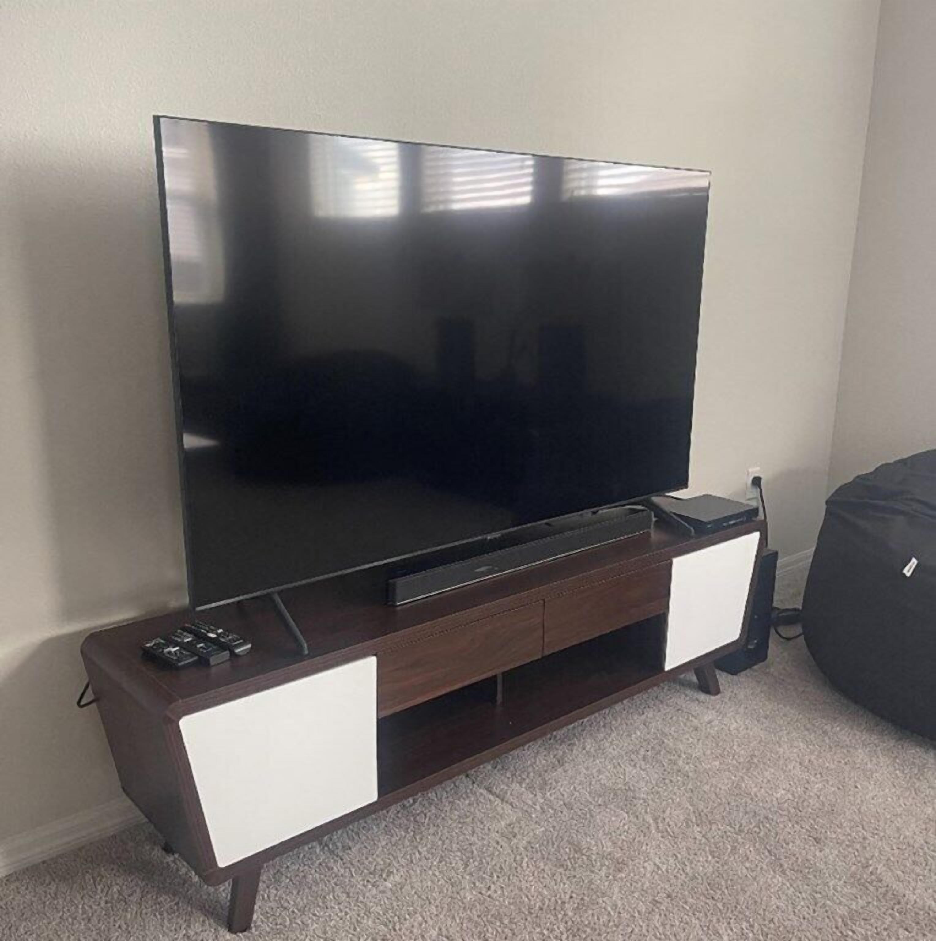 A flat-screen TV on a wooden TV stand with two white drawers.