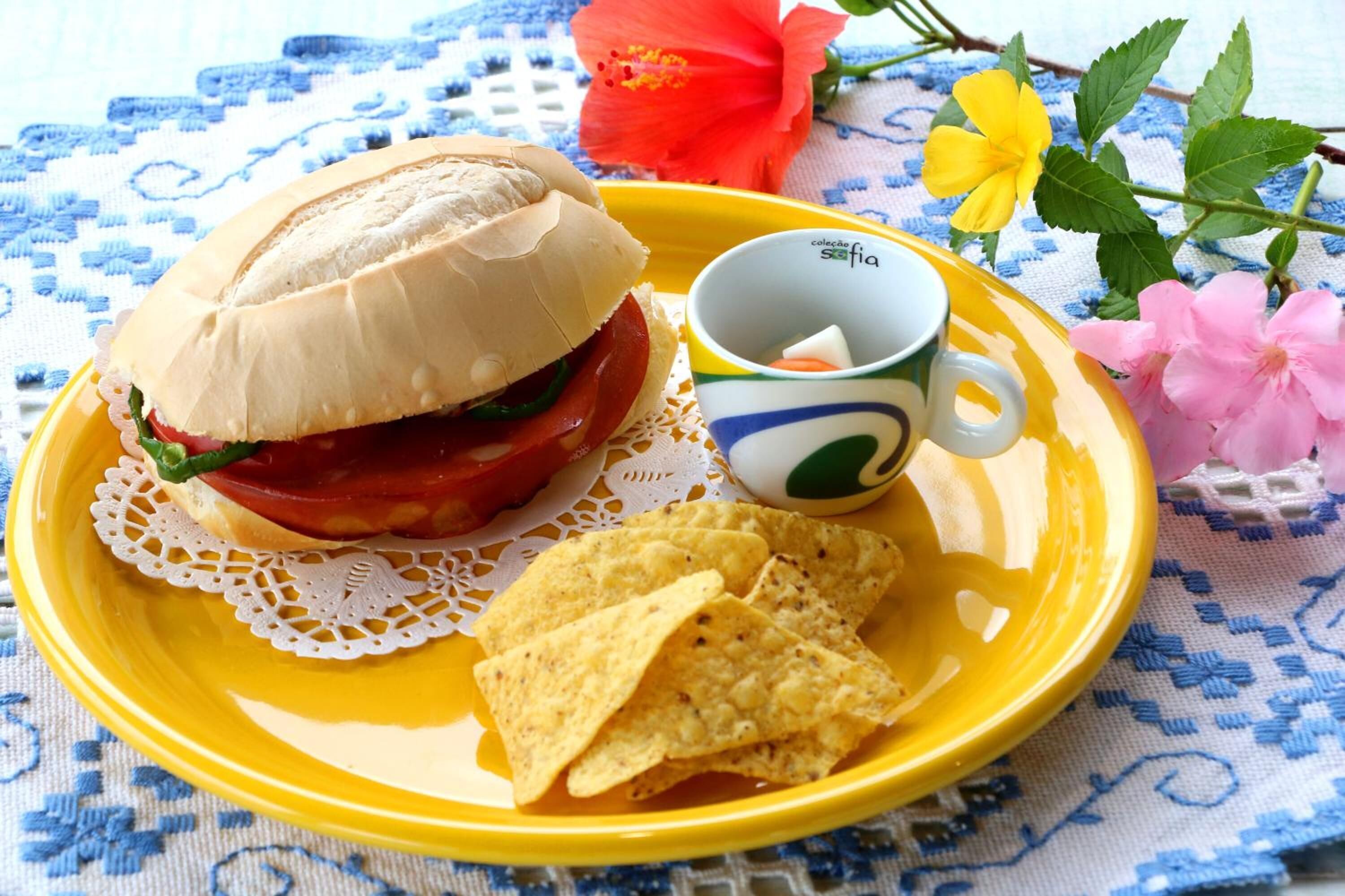 Een bord met een sandwich, chips en een beker.