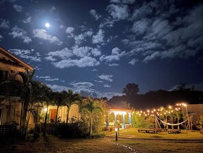 Un espace extérieur aménagé pour les soirées, avec un kiosque, des guirlandes lumineuses et une pelouse.