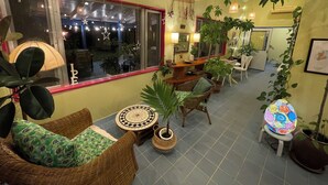 Un espace intérieur accueillant, aménagé avec des meubles en osier, des plantes en pot et un sol carrelé.