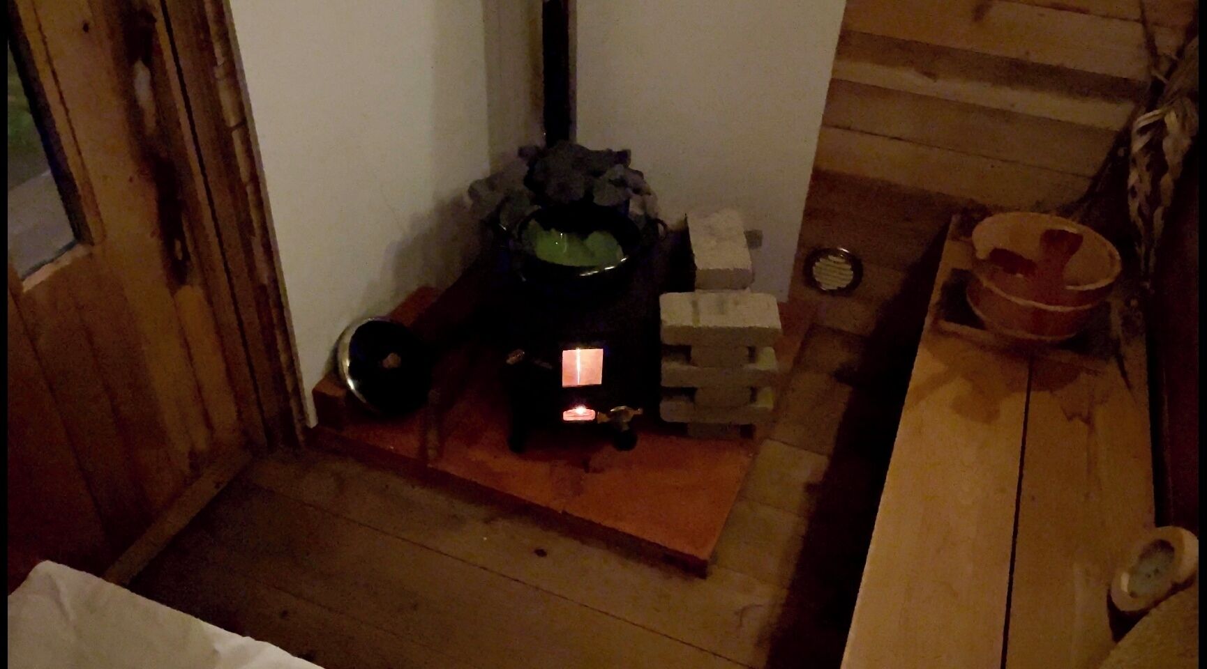 A room with a wood-burning stove, a small table, and a chair.