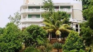 A multi-story building with balconies, surrounded by lush greenery and palm trees. - Luxury retreats, destination weddings, family reunions and social events (Las Terrenas)
