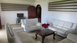 A living room with a white sofa set, a wooden coffee table, and a television on a stand. - Luxury retreats, destination weddings, family reunions and social events (Las Terrenas)