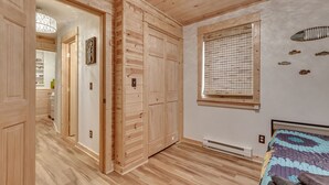 A room with wooden flooring, a bed with a patterned bedspread, a window with blinds, and a wall-mounted fish decoration. - ~New~ Yellowstone Rock Studio (Gardiner)