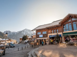 A mountain town with a stone building labeled "OFFICE DE TOURISME" and a shop named "MGM CONSTRUCTION".