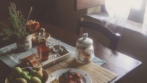 A dining table with a bowl of fruit, a plate of toast with jam, and a jar of jam.