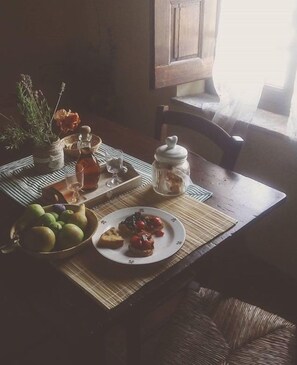 A dining table with a bowl of fruit, a plate of toast with jam, and a jar of jam.