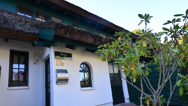 Un bâtiment avec une porte verte, une boîte aux lettres et une enseigne indiquant « Haus Straußried 17 ».