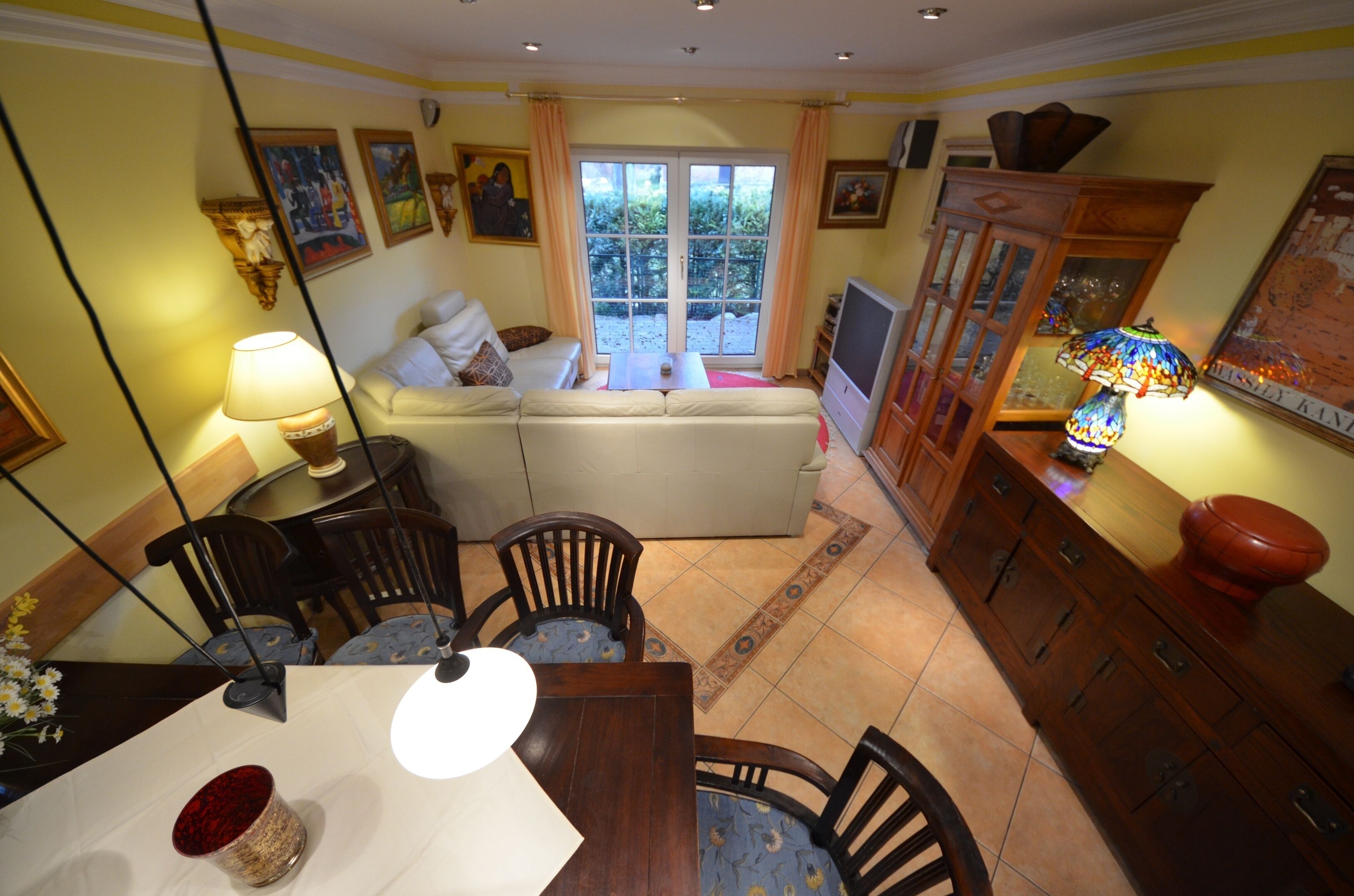 A living room with a sofa, dining table, chairs, and a TV.
