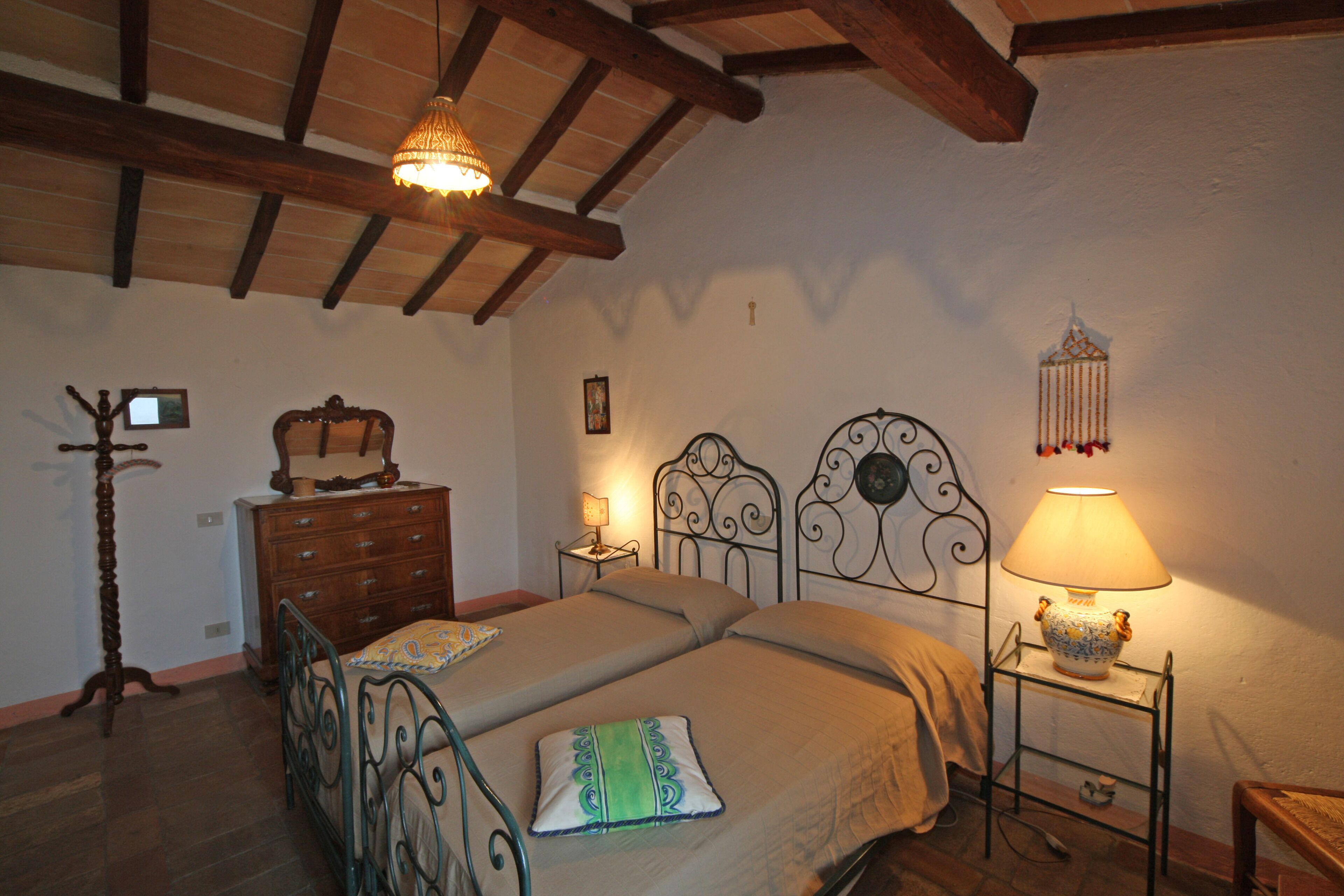 A bedroom with a bed, dresser, nightstand, lamp, and decorative items.
