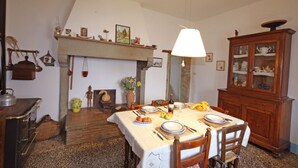 A dining room with a fireplace, wooden furniture, and a table set for a meal. - Farmhouse in the Tuscan countryside (Anghiari - Arezzo)