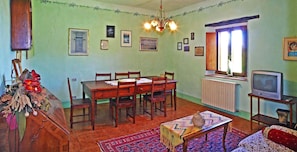 A dining area with a wooden table and chairs, a chandelier, and a television on a stand. - Farmhouse in the Tuscan countryside (Anghiari - Arezzo)