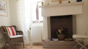 A cozy living room with a fireplace, wicker furniture, and a view of the street. - Vacation House Fiordilavanda (Martina Franca)