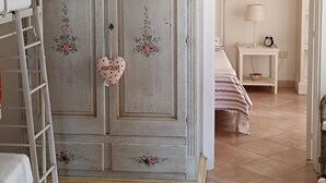 A bedroom with a vintage wardrobe, a ladder, a bedside table with a lamp, and a bed with a striped bedspread. - Vacation House Fiordilavanda (Martina Franca)