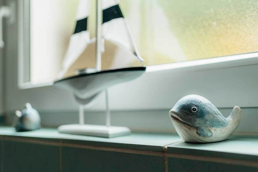 A model ship and a fish figurine on a shelf.