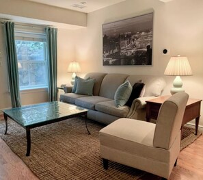 A living room with a sofa, armchair, coffee table, and lamps.