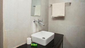 Et badeværelse med en hvid vask, et spejl, en håndklædestang og toiletpapir.