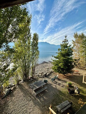 Eine Terrassenausrichtung am Seeufer mit Sitzgelegenheiten und Blick auf See und Berge.