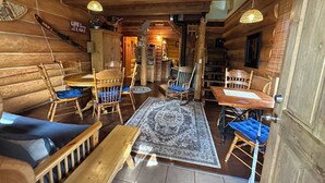 A log cabin interior with wooden furniture, a rug, and a fireplace.