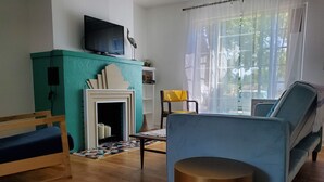 Een woonkamer met een televisie, een open haard, een bank, een stoel en een salontafel.