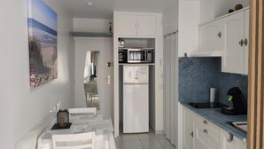 A compact kitchen with white cabinets, a microwave, a refrigerator, and a dining area with a table and chairs. - BEAUTIFUL APARTMENT 400 M FROM THE BEACHES OF MIMIZAN WITH INTERNET  (Mimizan)