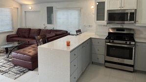 A modern kitchen with a central island, built-in oven, microwave, and white cabinetry.